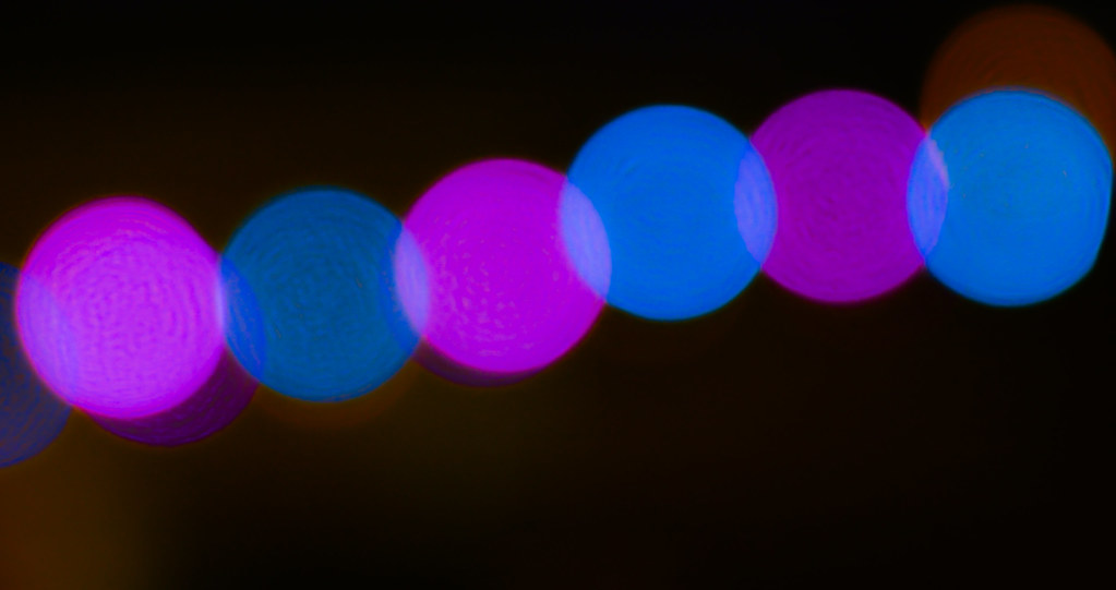 Blurry orbs of blue and pink light against a night sky.